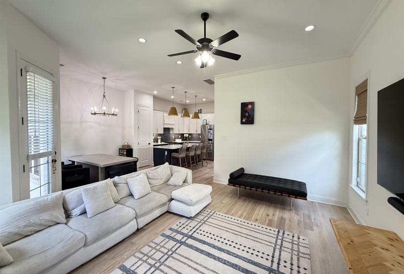Living area with ceiling fan, light wood finished floors, recessed lighting, a chandelier, and ornamental molding