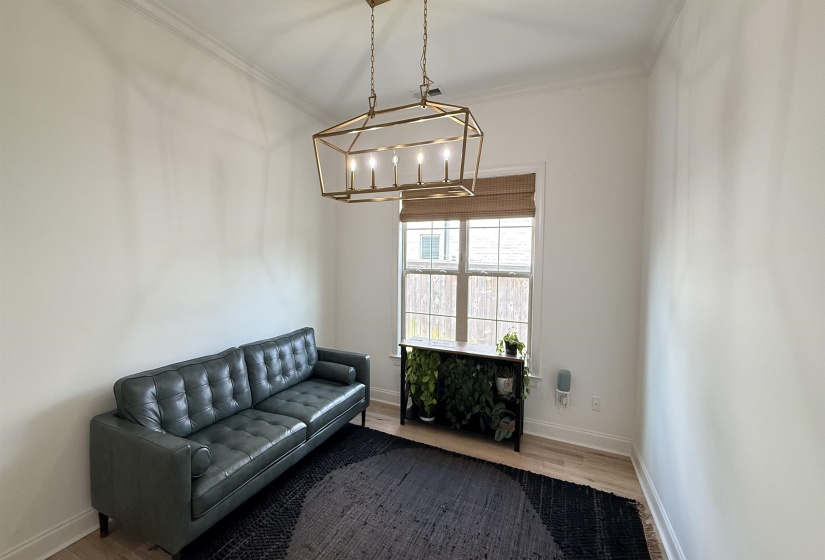 Living area with a chandelier, ornamental molding, and wood finished floors