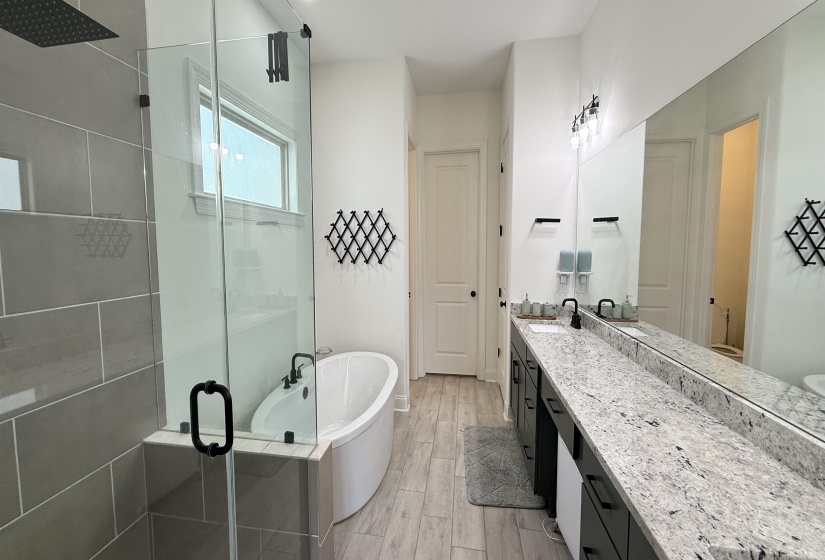 Bathroom with a stall shower, vanity, a freestanding bath, and wood finished floors