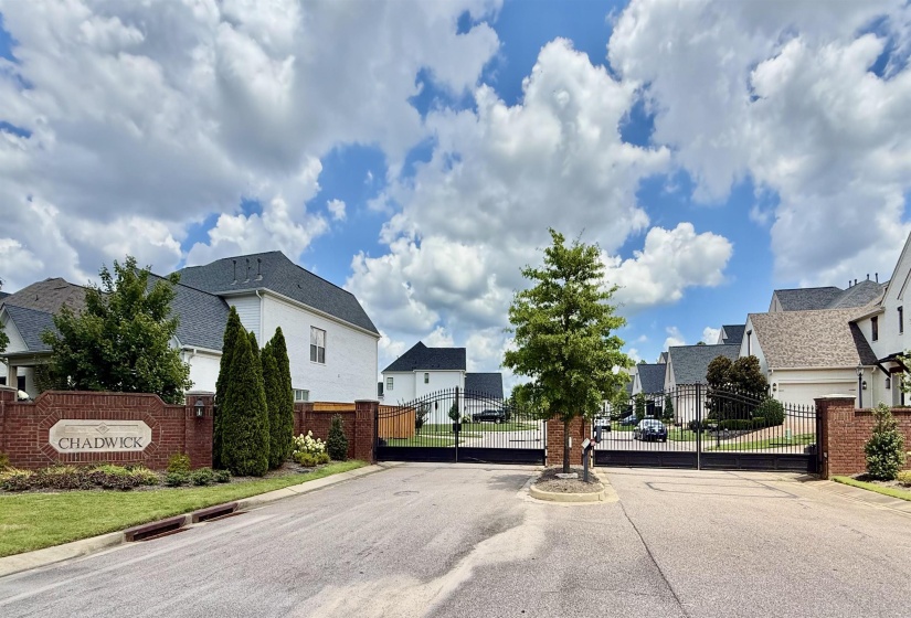View of asphalt street featuring a residential view, a gate, a gated entry, and curbs