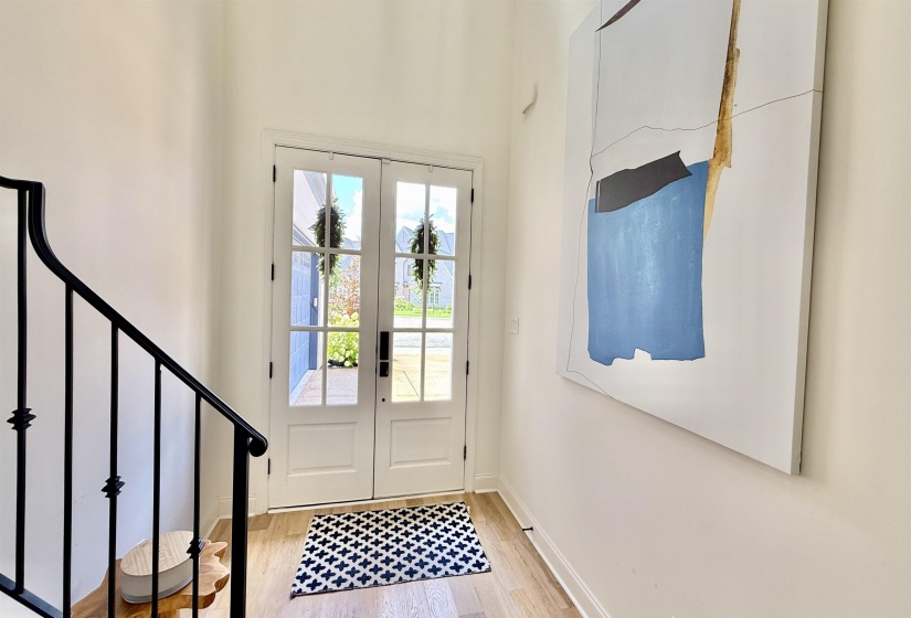 Foyer with light wood-style flooring, french doors, a high ceiling, and stairway