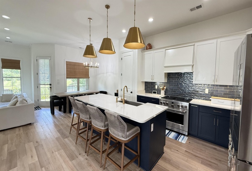 Kitchen with stainless steel appliances, open floor plan, light countertops, decorative backsplash, and a kitchen bar