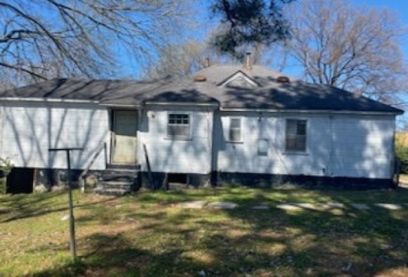 Rear view of house featuring entry steps and a lawn