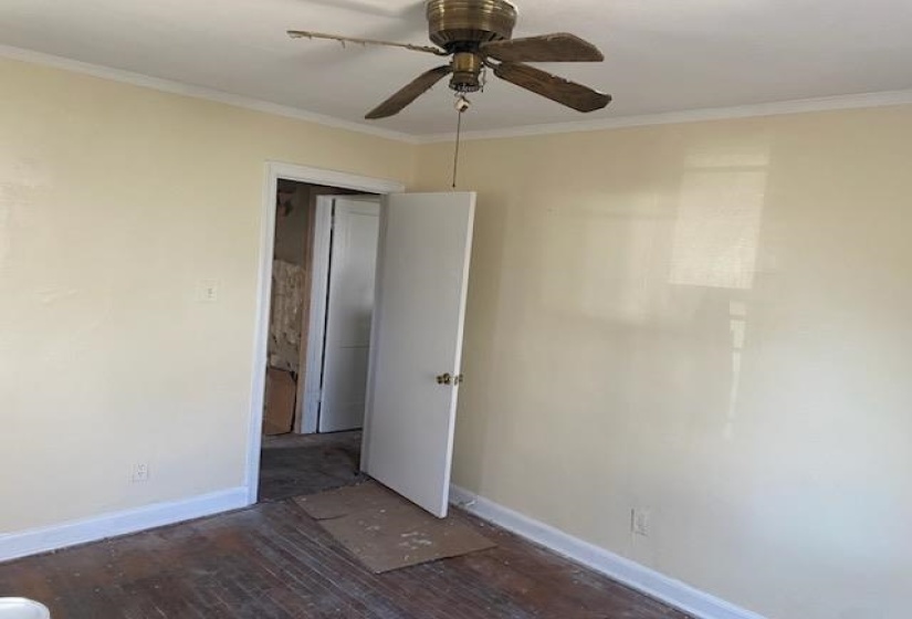Unfurnished bedroom with a ceiling fan, wood finished floors, baseboards, and ornamental molding