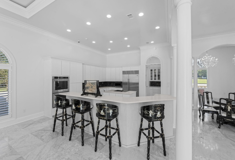 Kitchen featuring healthy amount of natural light, crown molding, arched walkways, a breakfast bar, and light marble finish floors