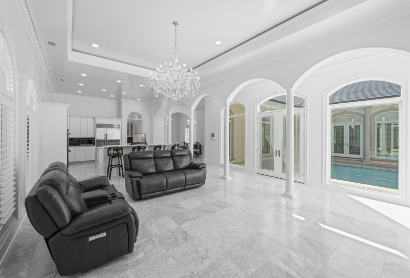 Living room with a tray ceiling, arched walkways, ornamental molding, a chandelier, and recessed lighting