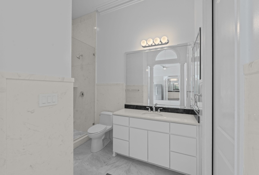 Bathroom featuring vanity, walk in shower, tile walls, light marble finish flooring, and a wainscoted wall