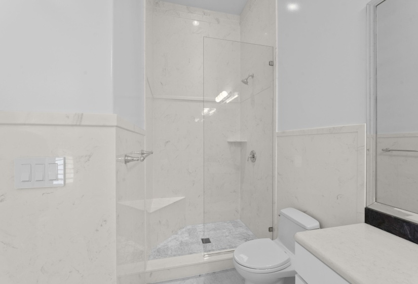 Full bath featuring vanity, a marble finish shower, tile walls, and a wainscoted wall