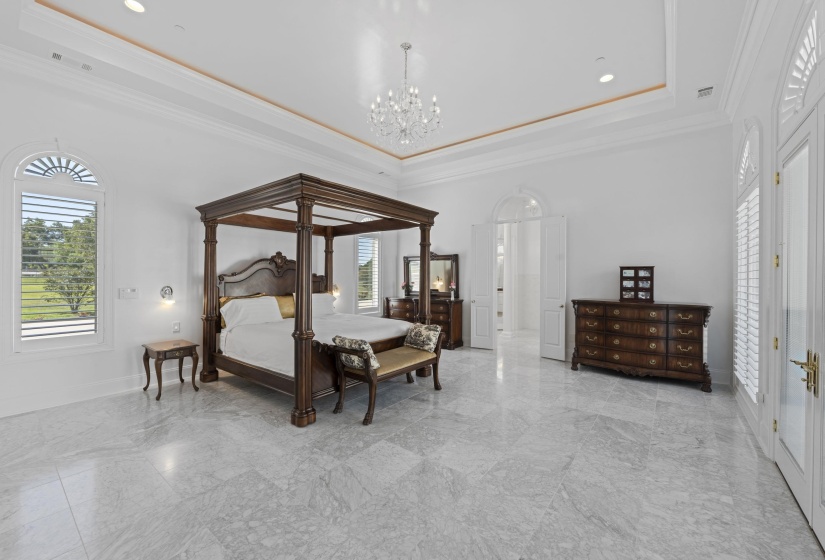 Bedroom with a raised ceiling, ornamental molding, a chandelier, light marble finish flooring, and recessed lighting