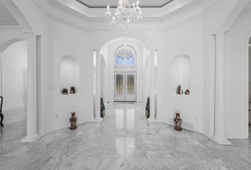 Hall featuring arched walkways, ornate columns, marble tiled flooring, a towering ceiling, and ornamental molding