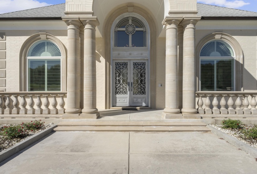 View of exterior entry with brick siding, a shingled roof, and a porch