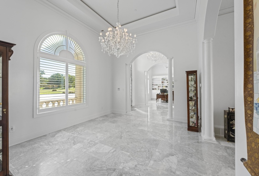 Interior space featuring arched walkways, a high ceiling, decorative columns, marble tiled flooring, and ornamental molding