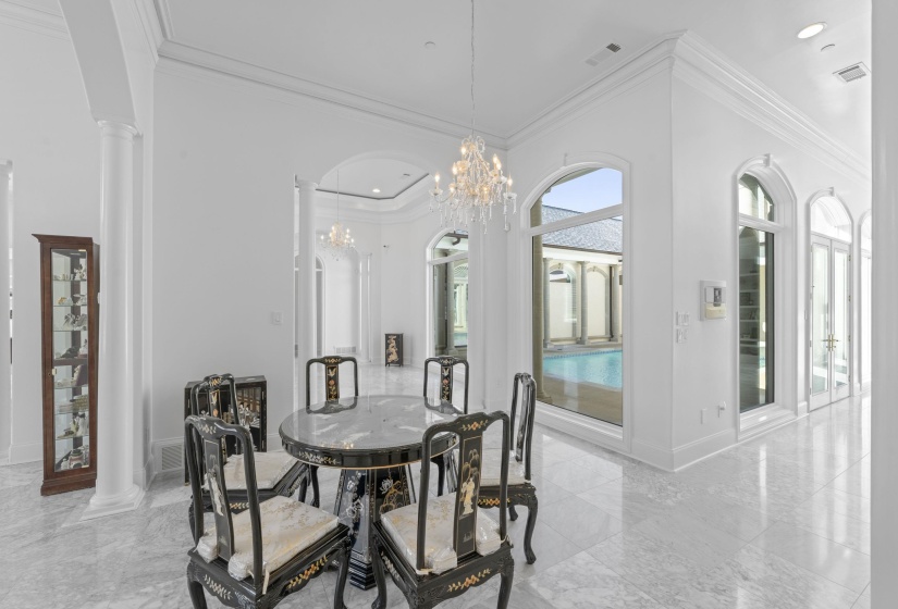 Dining room featuring ornate columns, ornamental molding, light marble finish floors, a chandelier, and recessed lighting