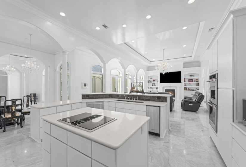 Kitchen with a chandelier, a tray ceiling, a warm lit fireplace, pendant lighting, and open floor plan