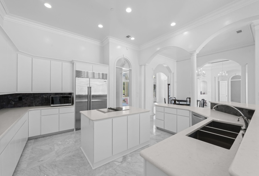 Kitchen featuring light marble finish floors, stainless steel appliances, modern cabinets, ornamental molding, and white cabinets