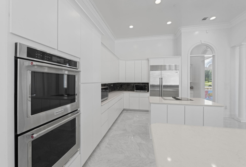 Kitchen featuring stainless steel appliances, ornamental molding, modern cabinets, white cabinetry, and a kitchen island