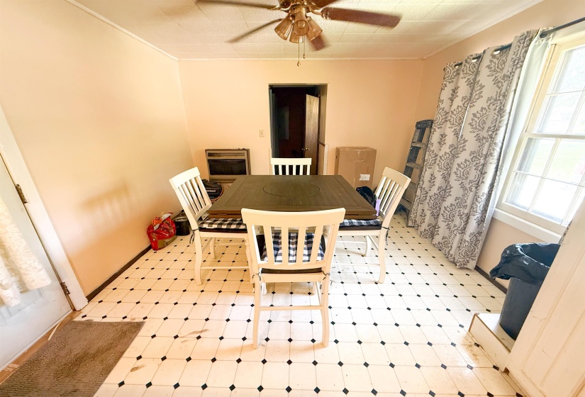 Room featuring black and white patterned tile flooring, light-toned walls, and a ceiling fan with wood-finish blades