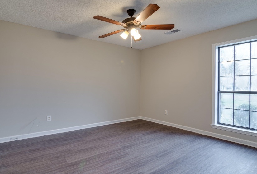 Room featuring wood-finish flooring, a ceiling fan with integrated lighting, and neutral wall paint