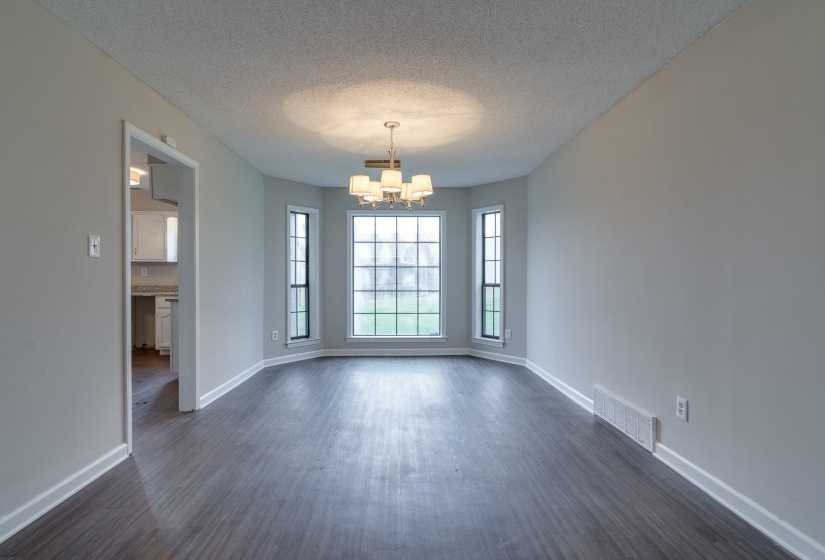 Dining area featuring a prominent bay window, wood-finish flooring, a contemporary chandelier, and light gray wall paint