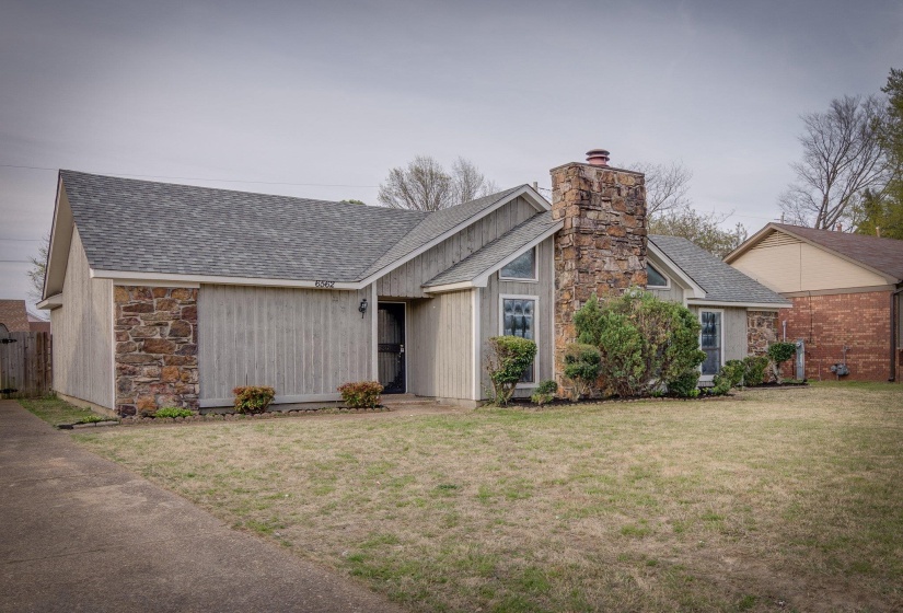 Exterior featuring a prominent stone chimney, vertical siding, and stone accent walls