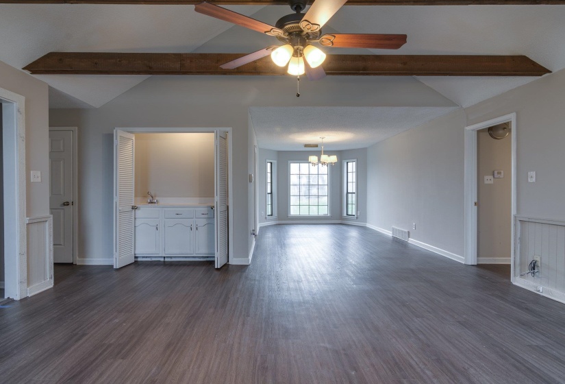 Vaulted ceiling with exposed wood beams and ceiling fan light fixture