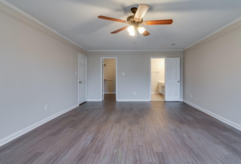 Spacious room featuring wood-finish flooring, neutral wall tones, and crown molding