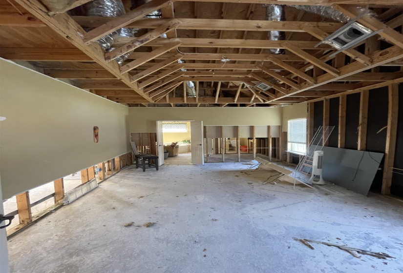 Vaulted ceiling with exposed wood beams, open framing, and visible ductwork
