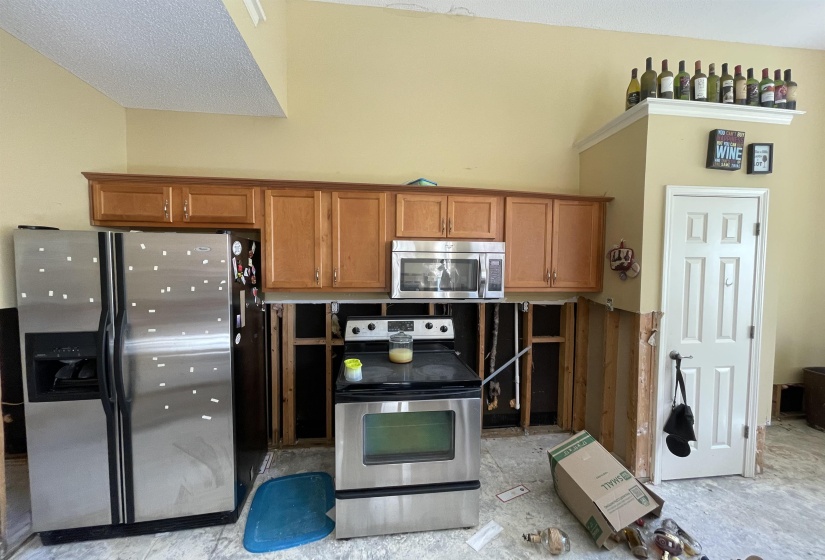 Kitchen featuring wood cabinetry, stainless steel side-by-side refrigerator, stainless steel electric range, and stainless steel microwave