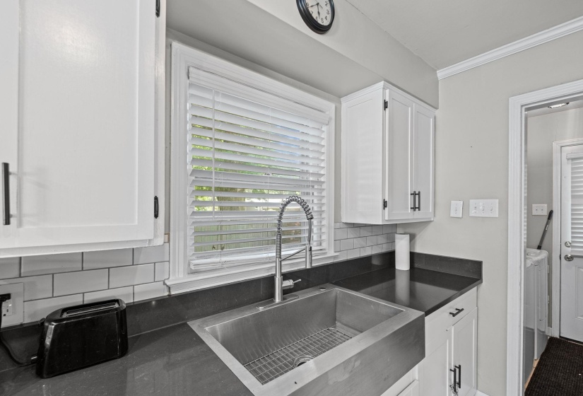 Kitchen area featuring white cabinetry with dark hardware, dark countertops, and a subway tile backsplash
