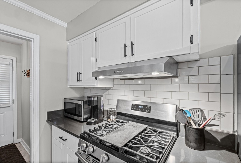 Kitchen featuring white shaker-style cabinetry with matte black hardware, dark countertops, and a white subway tile backsplash