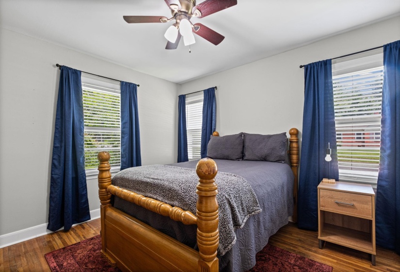 Bedroom with light-toned walls, wood-finish flooring, and white trim