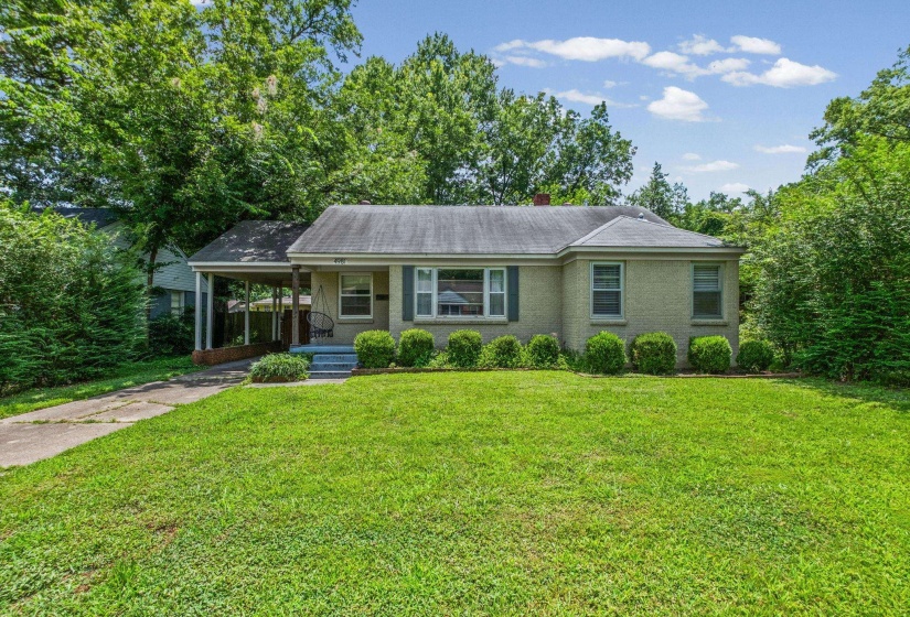 Ranch-style residence featuring a light-colored brick exterior, a covered carport, and a prominent front lawn