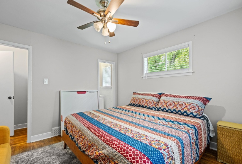 Bedroom featuring wood-finish flooring, a ceiling fan with light fixture, and a window with horizontal blinds