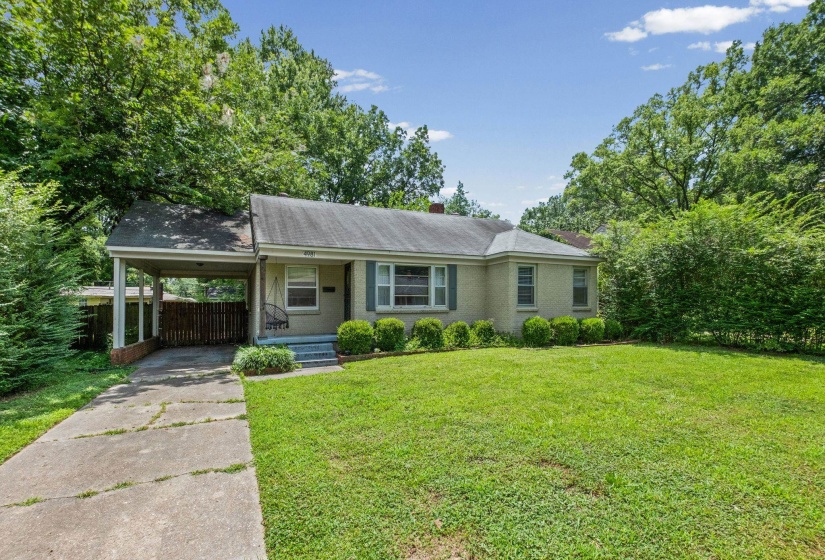 Brick exterior with a covered carport, concrete driveway, and front lawn