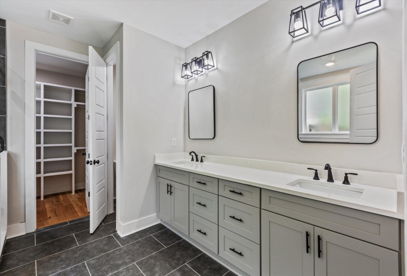 Bathroom featuring a dual vanity with light grey cabinetry, white countertops, and black hardware