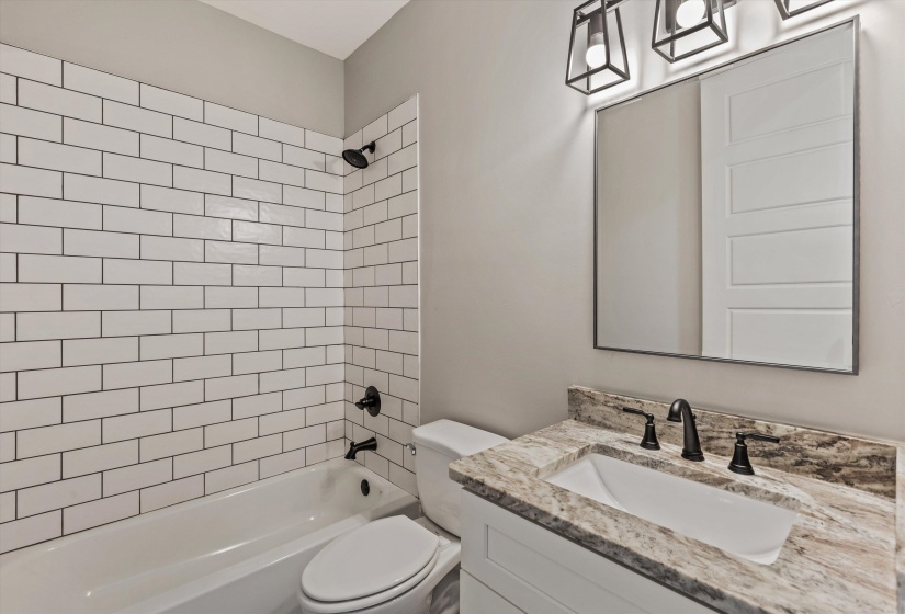 Bathroom featuring a white subway tile shower surround, a white bathtub, and matte black fixtures