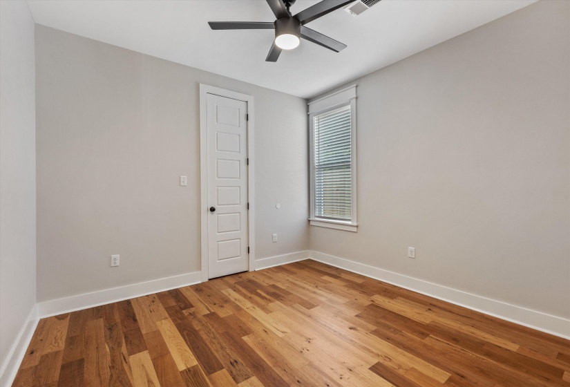 Room with wood-finish flooring, light neutral wall paint, and white baseboards