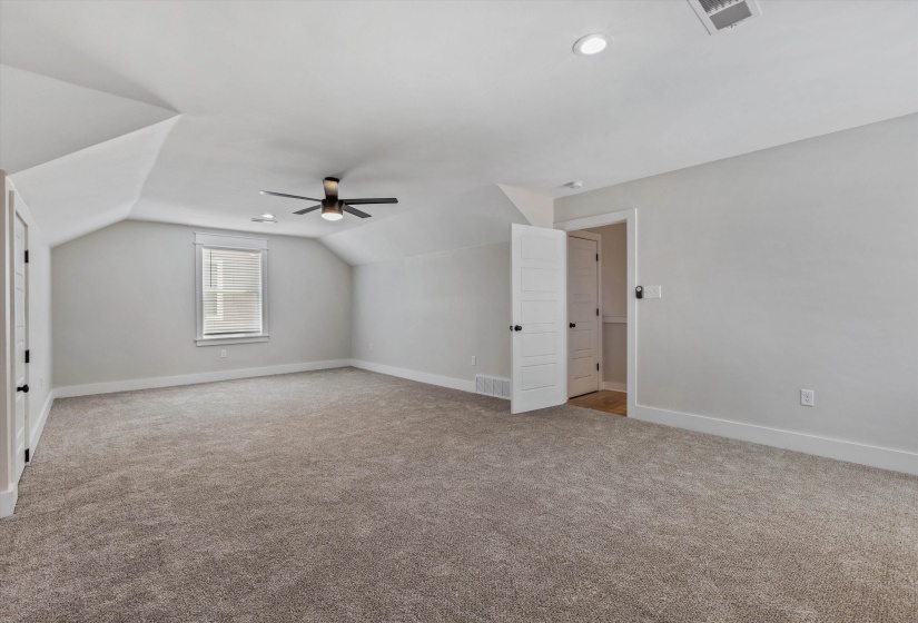 Spacious room featuring vaulted ceilings, recessed lighting, a modern ceiling fan, and a neutral carpeted floor