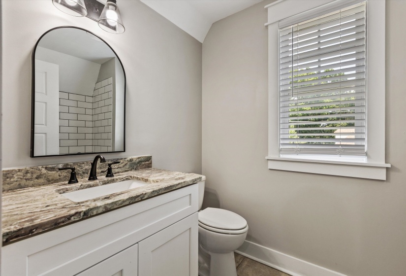 Bathroom featuring a white vanity with a patterned countertop, undermount sink, and dark-toned faucet