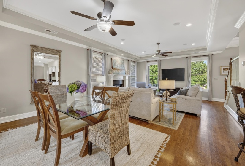 Hardwood flooring extends through this open concept space featuring recessed lighting, ceiling fans, crown molding, and abundant natural light from multiple windows