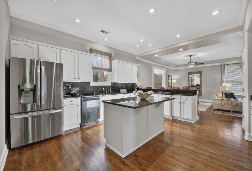 Kitchen featuring white cabinetry, dark countertops, a central island, recessed lighting, and wood-finish flooring