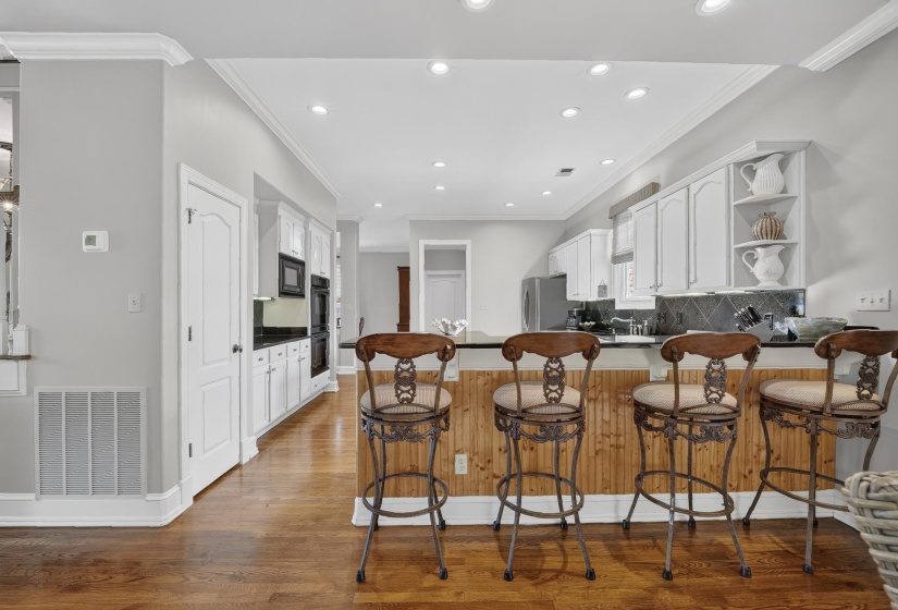 Kitchen with wood-finish flooring, white cabinetry, dark countertops, and recessed lighting