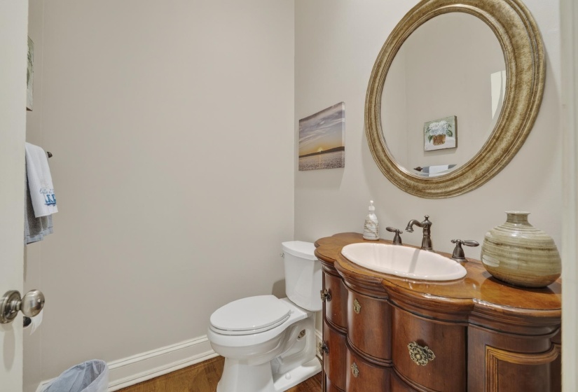 Powder room featuring a decorative wood vanity with an undermount sink, bronze-tone faucet, and a large round mirror with an ornate frame