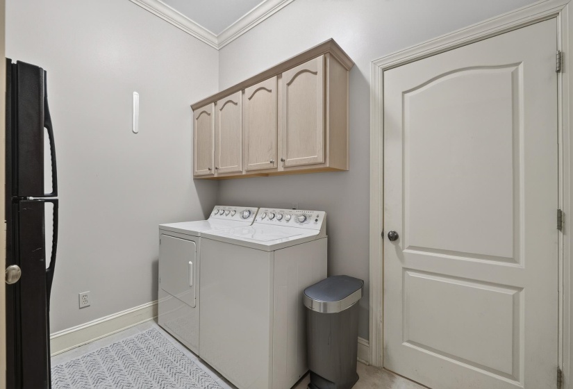 Laundry area featuring stacked cabinetry, crown molding, and a paneled door