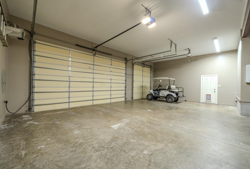 Spacious garage with multiple overhead doors, concrete flooring, and ample overhead lighting
