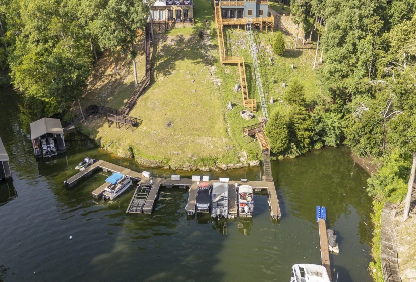 Waterfront property featuring multiple boat slips, a covered boat dock, and a wooden staircase descending to the water