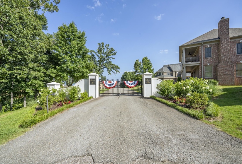 Gated entry with white pillar accents and a paved driveway