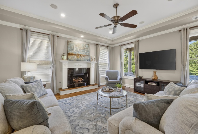 Living area featuring a traditional fireplace with white mantel, wood-finish flooring, and crown molding