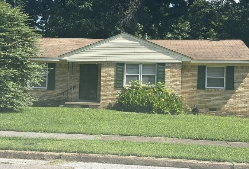 Brick exterior with a gabled entry, featuring a shingle roof and green window shutters