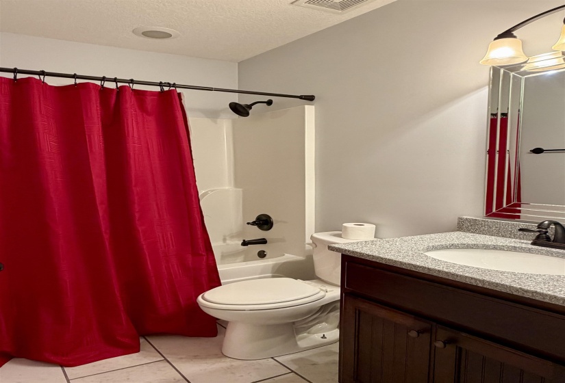 Bathroom featuring a single vanity with a speckled countertop, integrated sink, and dark wood cabinetry
